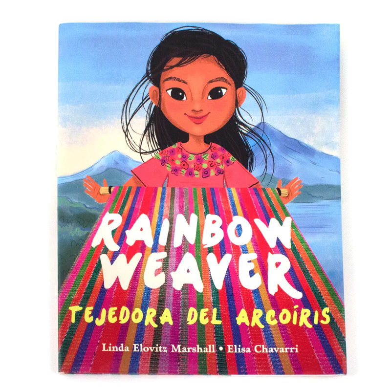 Cover of the book Rainbow Weaver. Features the protagonist, a young child, standing behind their weaving with mountains in the background.